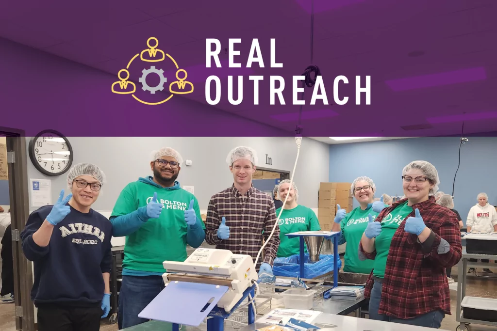 A group of people giving the thumbs up at a food packing event