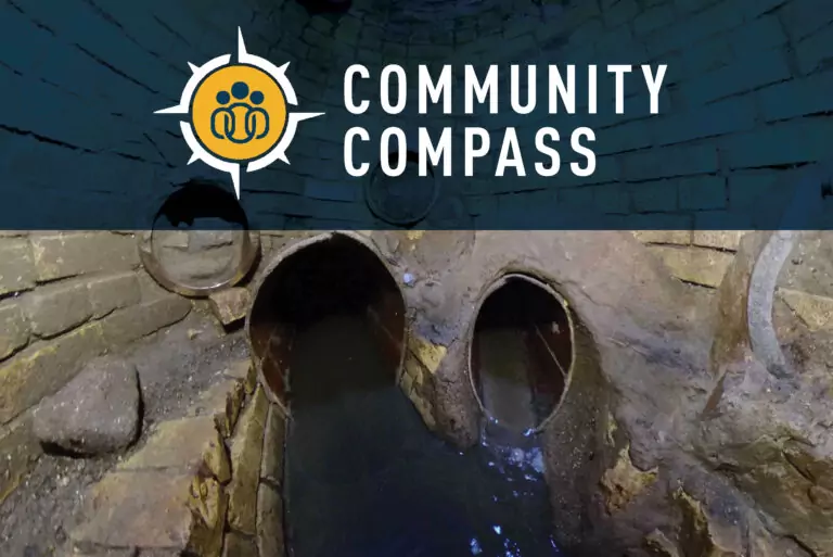 A brick-lined underground tunnel with murky water flows through two arched openings. The top of the image features the Community Compass logo and text on a blue background.