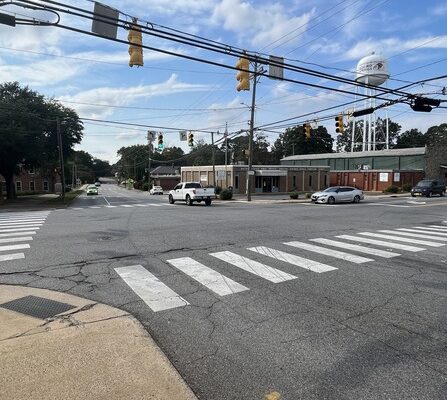 A crosswalk with cars and buildings in the background