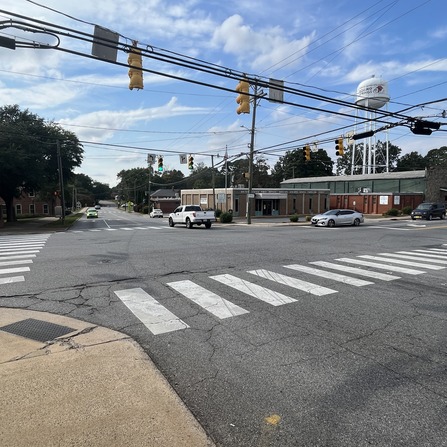 A crosswalk with cars and buildings in the background