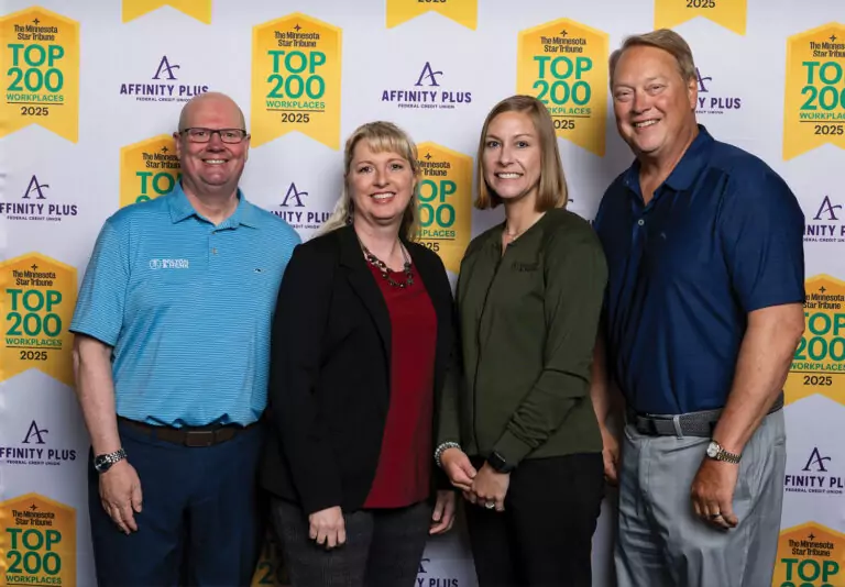 Four individuals are standing in front of a backdrop that features the logos 'Affinity Plus' and 'The Minnesota Star Tribune Top 200 Workplaces 2025.