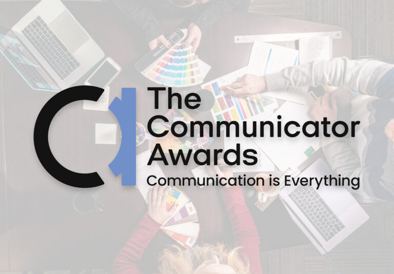 Overhead view of people working with laptops, papers, and color swatches at a table. Overlaid text reads: The Communicator Awards. Communication is Everything with a logo on the left.