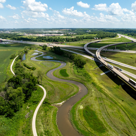 A meandering stream with trees next to a highway