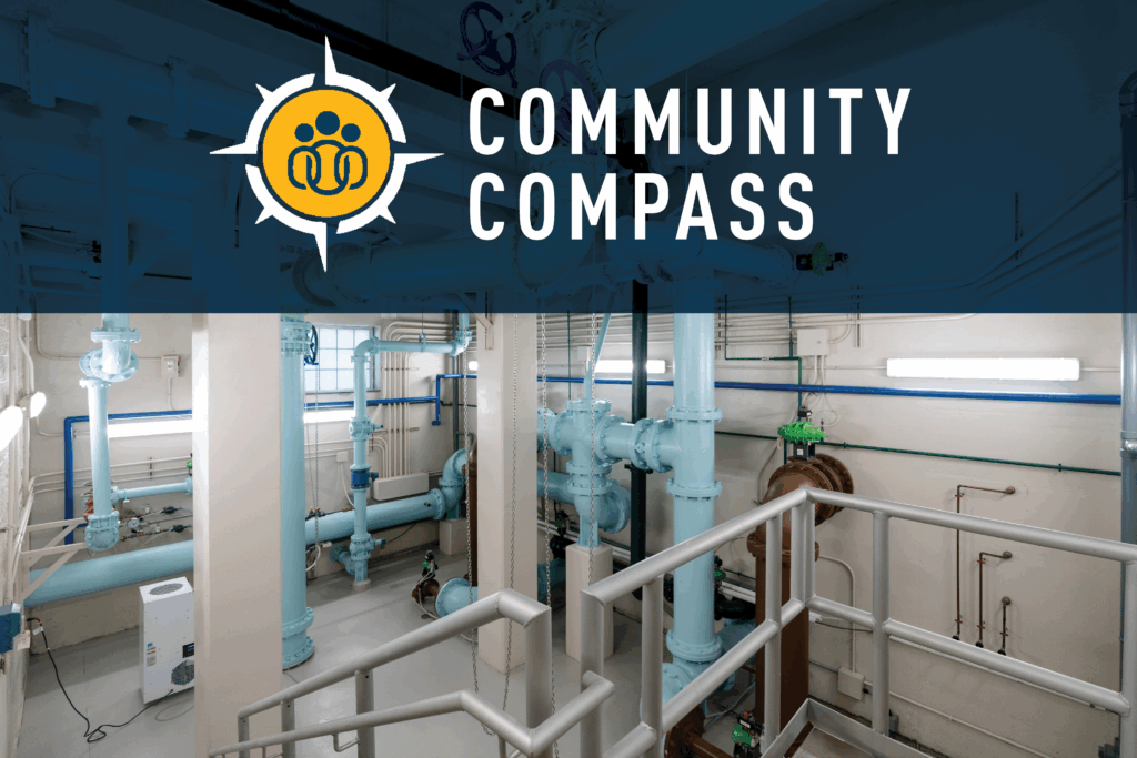 Industrial room with light blue pipes and metal railings. Overlaid at the top is a blue banner with a yellow and white compass logo and the words “COMMUNITY COMPASS” in bold white letters.