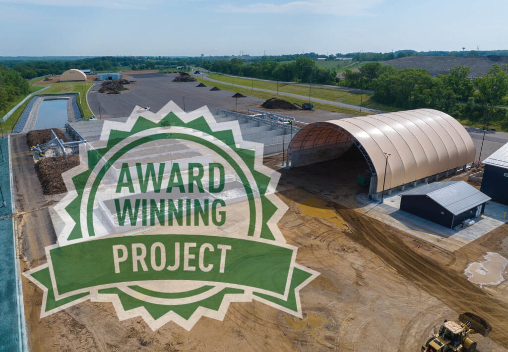 Aerial view of an industrial site with buildings, equipment, and surrounding greenery. A large green badge overlay reads AWARD WINNING PROJECT.