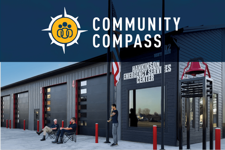 Three people sit and talk outside a modern emergency services center with red garage doors and American flags. Text highlight reads, Community Compass.