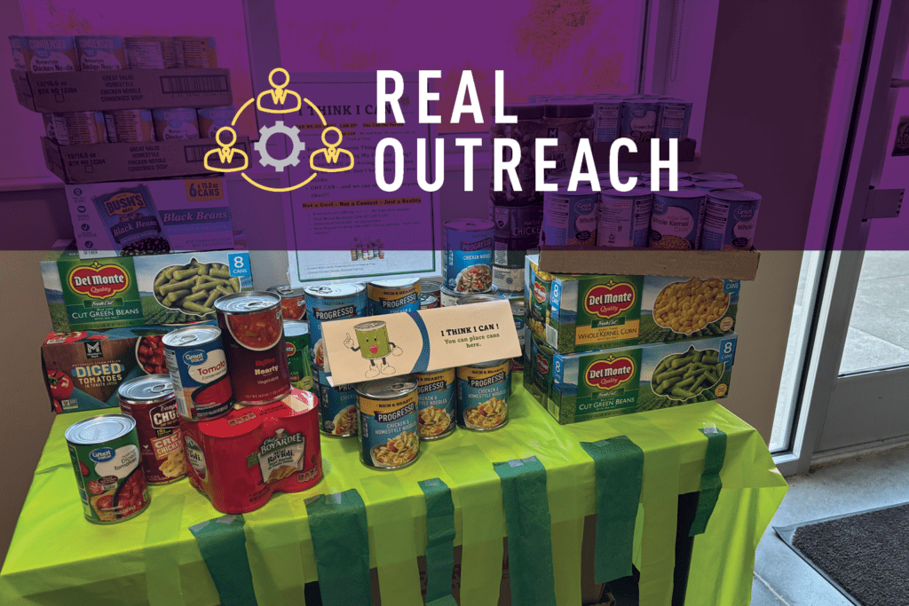 A table covered with canned goods, including beans, tomatoes, and vegetables, is decorated with green streamers. Boxes of food are stacked behind it. Text over the image reads REAL OUTREACH—celebrating the Season of Giving Back—with three connected gears.