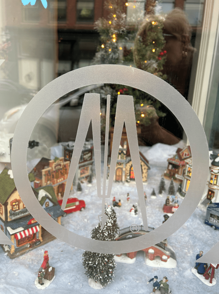 A frosted glass BMI decal on the window, framing a mini winter village of houses, snowy trees, and festive figurines.