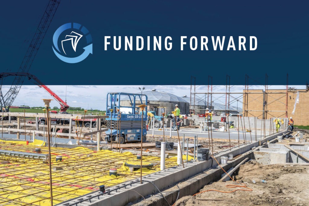 A construction site with workers, scaffolding, and building materials. Above, a blue banner displays a circular arrow logo and the text FUNDING FORWARD, highlighting water infrastructure funding. The sky is clear with some clouds.