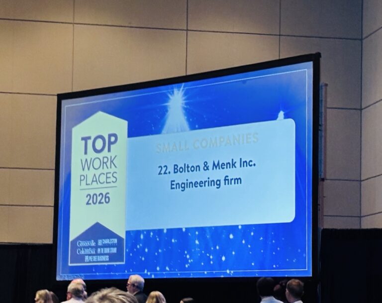 A presentation screen displays 2026 South Carolina Top Workplace and lists 22. Bolton & Menk Inc. Engineering firm under Small Companies at an indoor event, with people gathered below the screen.