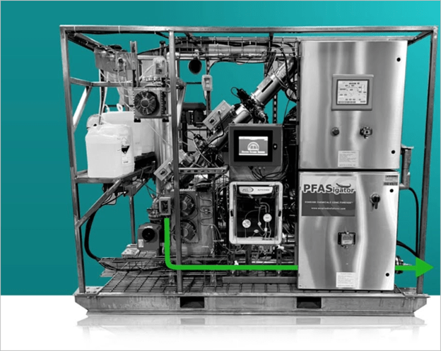 Industrial water treatment machine labeled PFASigator with various pipes, gauges, tanks, and a digital display, displayed against a teal background. A green arrow on the bottom right suggests water flow direction.